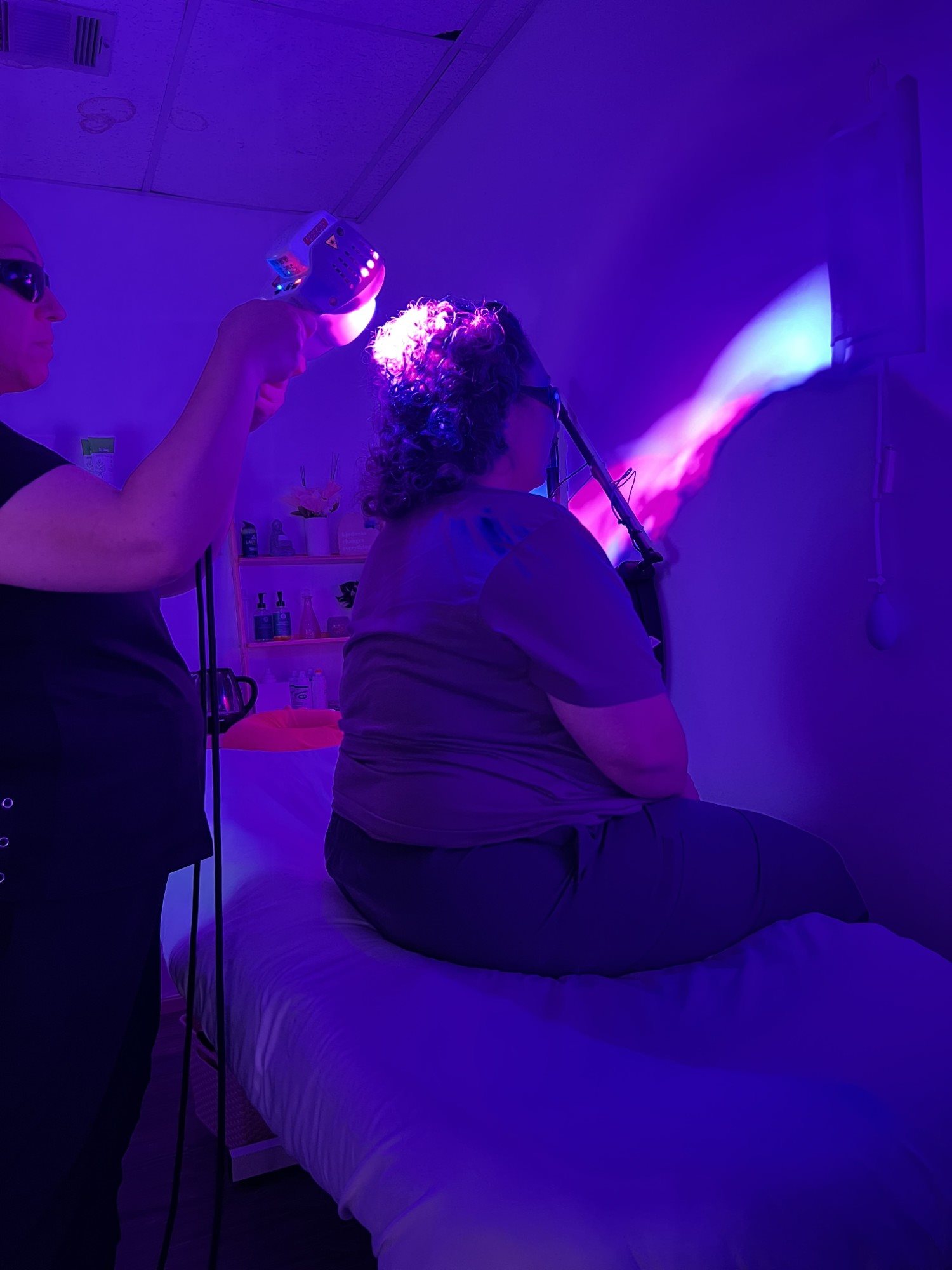 Nurse holding a Firefly light therapy handpiece over a seated client's scalp